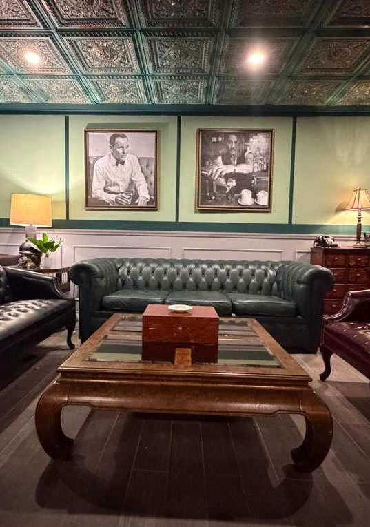 The green lounge with chesterfield sofas beneath framed portraits