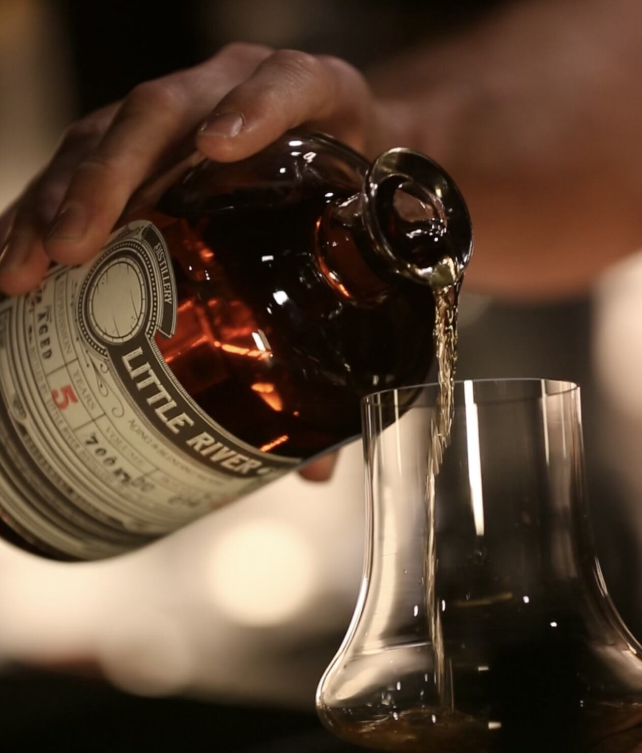 Little River rum being poured from a bottle into a tasting glass